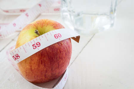Apple and measuring tape - healthy eating and dieting concept