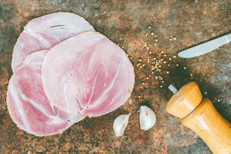 Sliced smoked ham with garlic on stone background