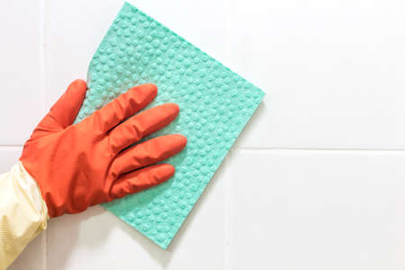Hand and a blue cloth cleaning on a white wallの写真素材