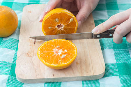 Woman cutting fresh oranges on tableの写真素材