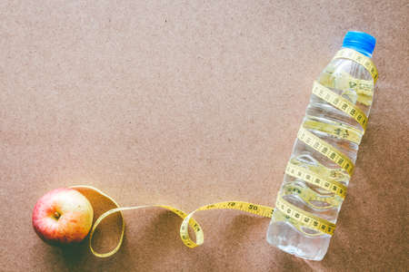 Water bottle and apple and tape measure on wooden background with copy space - Healthy food and fitness conceptの写真素材