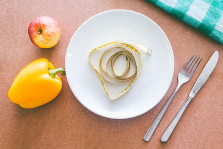 Empty plate, fork, knife and tape measure on wooden table - Healthy food conceptの写真素材