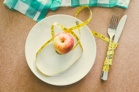 Apple with tape measure over plate on wooden table -Healthy food conceptの写真素材