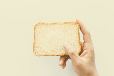 Hands hold a slice of bread on white backgroundの写真素材