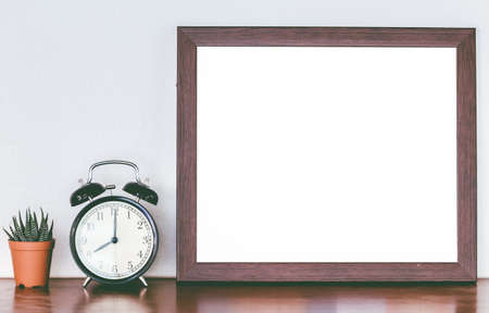 Wooden frames and alarm clock with cactus on tableの写真素材