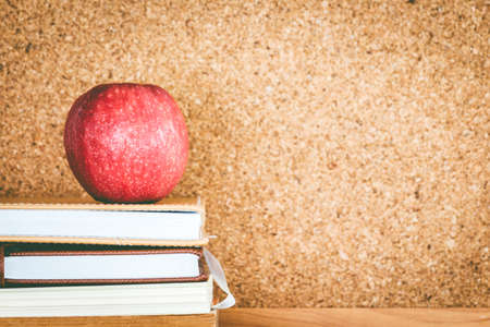 Apple and books on cork board, empty space for textの写真素材