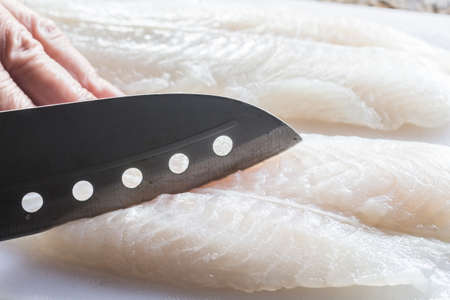 Cutting fish on white cutting boardの写真素材