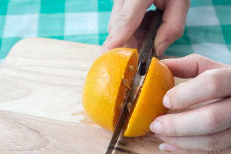 Woman cutting fresh oranges on tableの写真素材