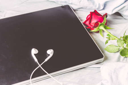 Laptop and red rose  on white bedの写真素材