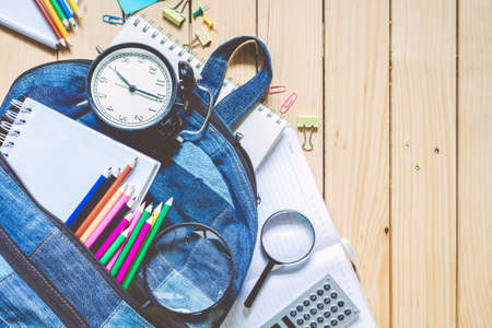 Backpack with school supplies on wooden backgroundの写真素材