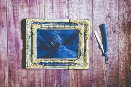 Vintage frame and hairdressing tools on wooden backgroundの写真素材