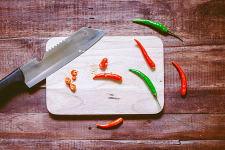 Chili pepper with Knife on chopping board on wooden background