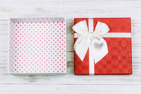 Red gift box with ribbon on wooden background