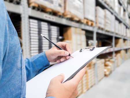 Man checking  list on clipboard in a warehouseの写真素材