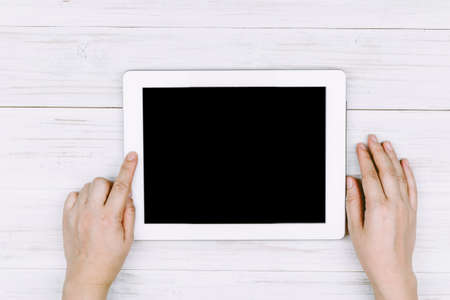 Female hands using tablet pc on wooden tableの写真素材