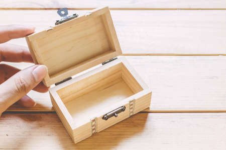 Hands hold a empty(blank) opened wooden box on wooden tableの写真素材