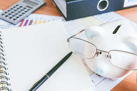 Piggy bank and calculator on business documents backgroundの写真素材