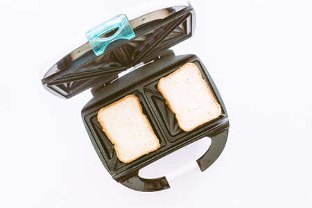 Toaster with bread slices making machine tool fast on white backgroundの写真素材