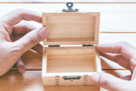 Hands hold a empty(blank) opened wooden box on wooden tableの写真素材