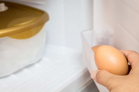 Hand holding chicken eggs in the refrigerator