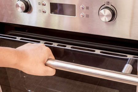Hand opening the oven door