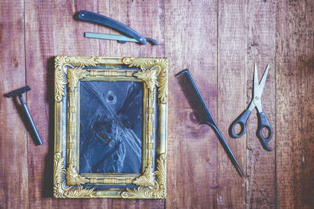 Vintage frame and hairdressing tools on wooden backgroundの写真素材