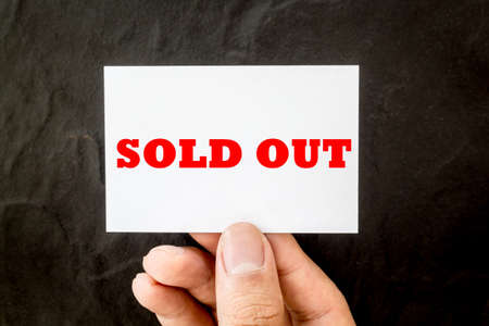 Hands holding blank business card with text sold out on black backgroundの写真素材