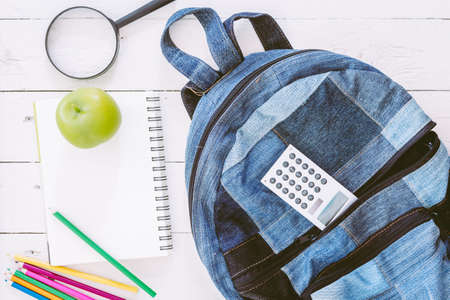 Backpack with school supplies on wooden background