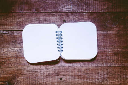 Open blank notepad with empty white pages on wooden table