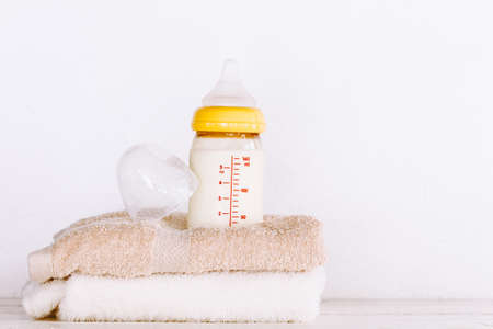 Baby bottle with milk on towel on wooden table