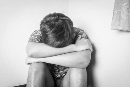 Man sitting depression on the floor near the wall - black and white tone