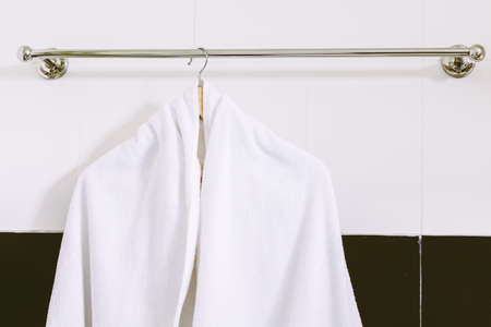 White towel on stainless steel towel hanger on wall in bathroomの写真素材