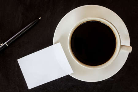 Business card and coffee cup on black background