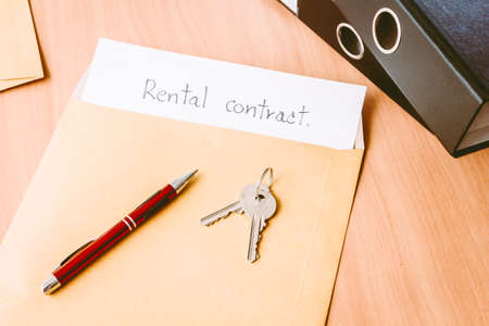 Rental contract with red pen and keys on wooden tableの写真素材