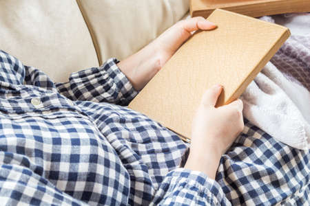 Woman holding a book on the sofa