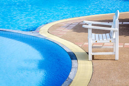 White wooden sunbed on  floor beside swimming pool