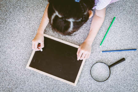 Little girl writing something on blackboardの写真素材