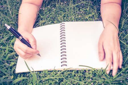 Hands with pen writing on notebook in parkの写真素材