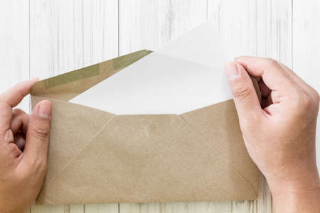 Hand hold a envelope and paper on the wooden background