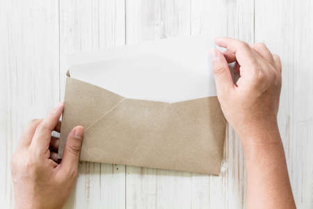 Hand hold a envelope and paper on the wooden backgroundの写真素材
