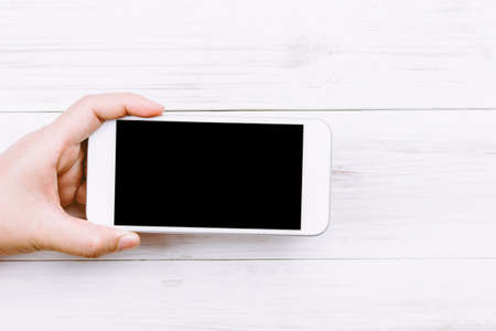 Women hand holding smartphone on wooden background