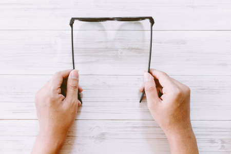 Hand holding eyeglasses on wooden backgroundの写真素材
