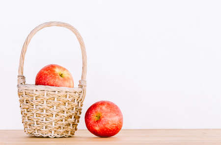 Apples in basket on wooden tableの写真素材