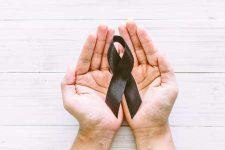 Black ribbon in hand on wooden background