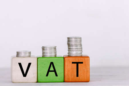 VAT Concept with wooden block with stacked coinsの写真素材
