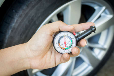 Hand holding pressure gauge for checking tire pressureの写真素材