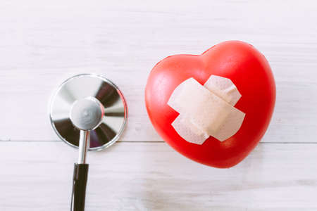 Stethoscope with red heart on wooden background