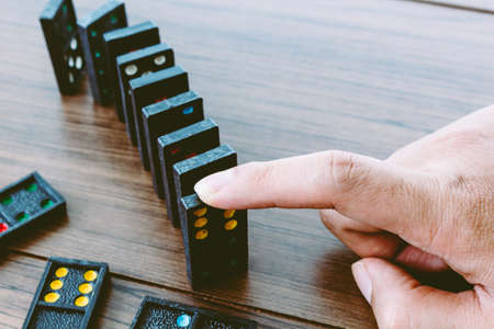 Hands playing domino on wooden tableの写真素材
