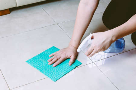 Woman  with cloth and  spray cleaning floor at homeの写真素材