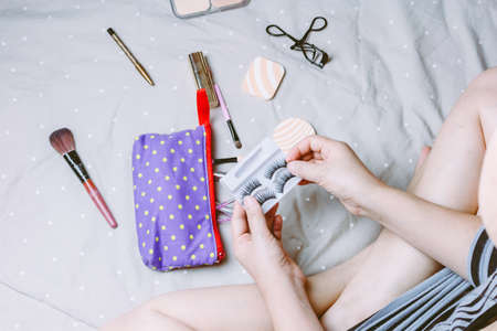 Woman applying makeup on the bed